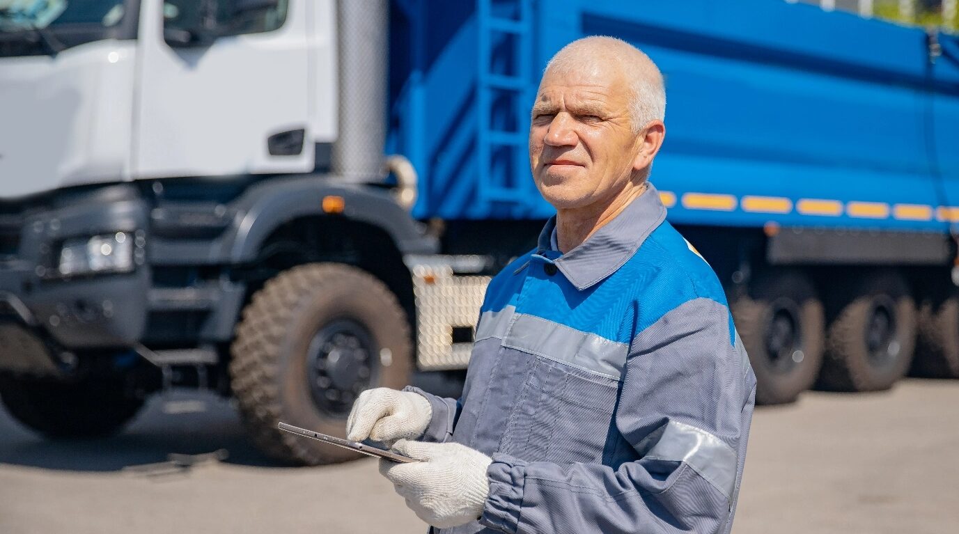 a worker wandering while holding a tablet with truck behind